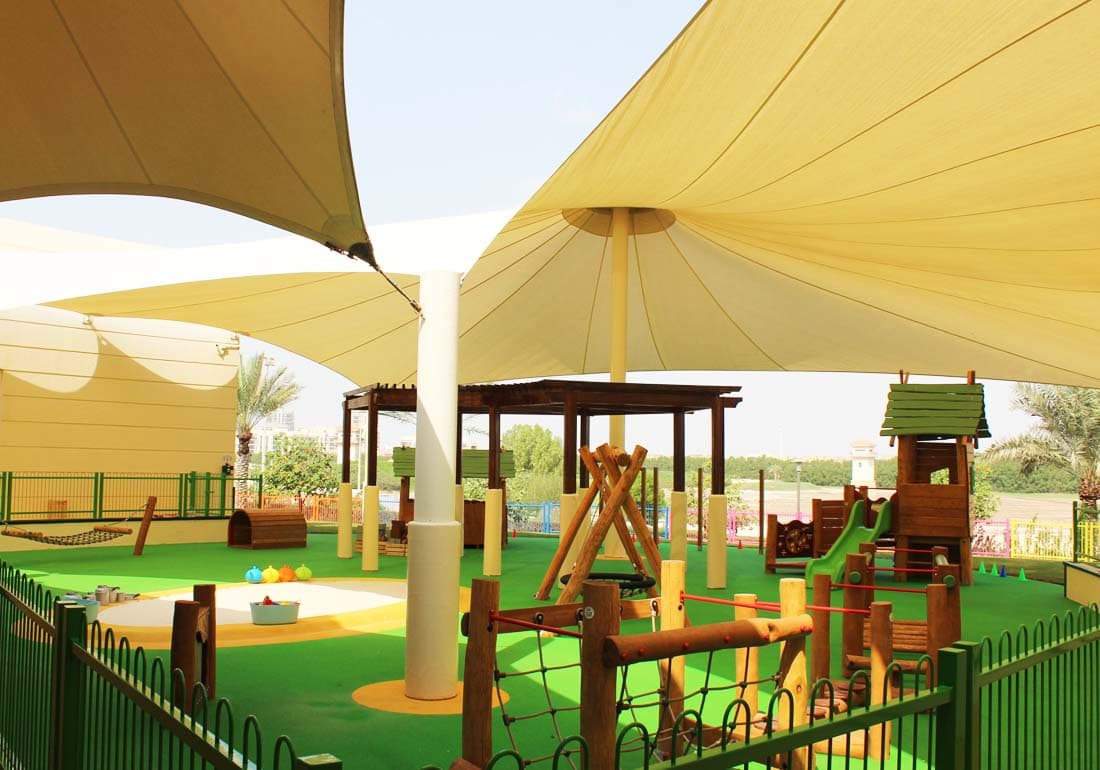 Tensioned shade sail over a school sandpit and play equipment