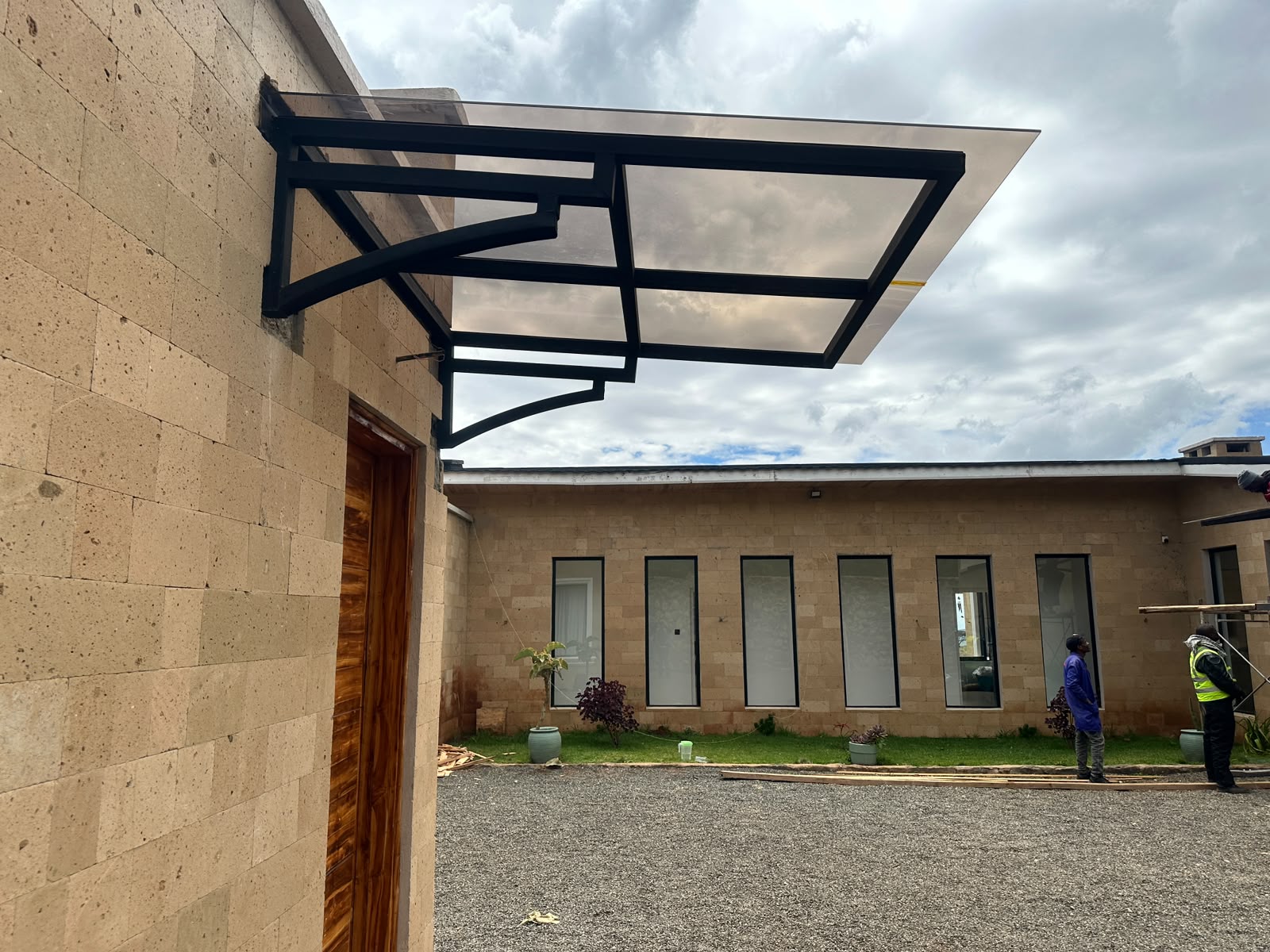 Wall-mounted polycarbonate entrance canopy with clean steel detailing